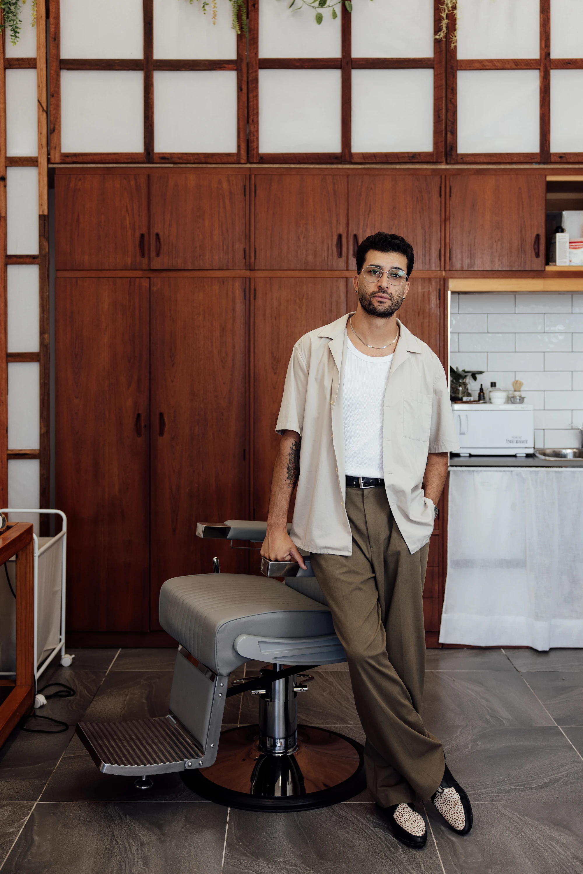 Eser Barber standing next to a barber chair in his studio